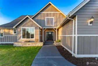 Wide sidewalk into front door lined with flowerbeds.