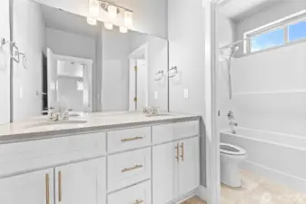 A spacious upstairs bathroom featuring double sinks and a designated area for the toilet and shower, ensuring functionality and privacy.