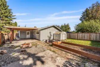 Large backyard with garden space, shed, and fire pit.