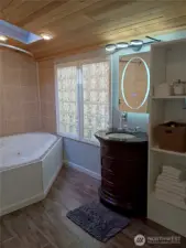 Primary en suite bathroom with jetted corner tub, cedar ceilings and skylight..