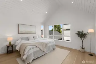 The primary suite is a true retreat, featuring vaulted ceilings and large windows that frame the neighborhood views.