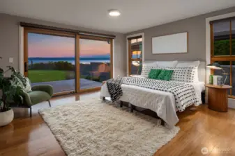 Primary bedroom steps to back deck, across lawn and onto the shores of Puget Sound.