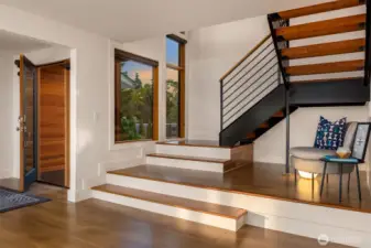 Architecturally interesting steel stairs with large windows lead with outdoor light from main to upper level.