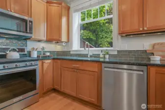 Abundance of kitchen cabinets, slab granite counter tops, tile back splash & window to green outlooks.