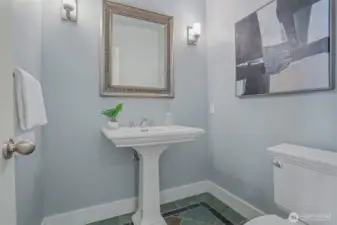 Main level slate power room with wall sconces and pedestal sink.