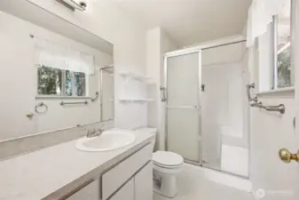 Light and bright primary bath has a shower with a bench seat in it.
