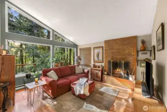 Light and bright windows open this spacious living room with vaulted ceilings and the coziest wood burning fireplace