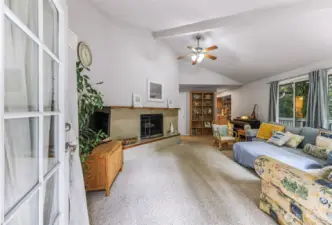 Airy living room with vaulted ceiling and a woodland view.