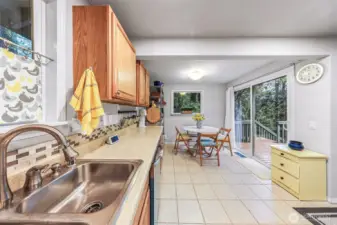 Tiled eat-in kitchen with new appliances and slider to side stairway off the cedar deck.