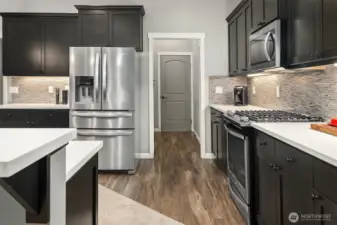 Showcasing stainless-steel appliances and rich luxury vinyl plank flooring, this kitchen combines modern style with everyday durability.