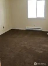 Large bedroom with wall to wall carpet, baseboard heat and plenty of natural light from the window.