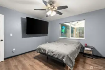 This photo showcases the inviting primary bedroom, featuring beautifully installed hardwood flooring that adds warmth and character to the space, complemented by a practical and stylish ceiling fan for optimal comfort.