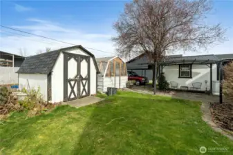 Storage shed, greenhouse and covered patio adjacent to the studio outbuilding.