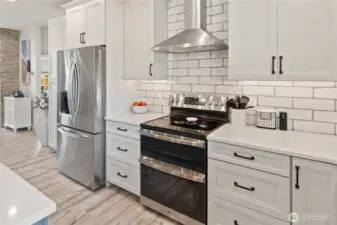 Subway tile, stainless steel appliances, a farmhouse sink, and quartz countertops come together to create a beautiful and well-appointed kitchen space.