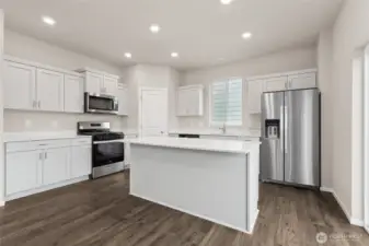 Bright and spacious kitchen featuring white quartz countertops, a center island, stainless steel appliances. Photos are representative only and may display different color packages and/or upgrades.