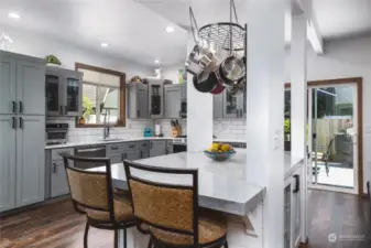 The stylish custom cement island has a beautiful smooth finish, additional built in cabinets and is finished with shiplap. You'll love the hanging pot rack too!