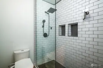 The custom walk-in shower displays gorgeous tile work and a rainfall shower head.
