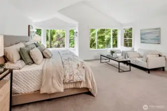 The luxurious primary suite is a true retreat, offering generous proportions, vaulted ceilings, and serene views of lush greenery through oversized windows