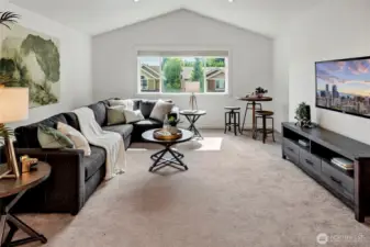 This spacious second-floor bonus room is the perfect flex space—ideal for movie nights, playtime, or a teen hangout. Nestled between three bedrooms, it features vaulted ceilings, plush carpet, and a large window that brings in natural light. With room for a sectional sofa, media center, and even a game or craft table, this inviting area adds valuable versatility to the home.