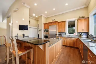 This stunning kitchen has an eating bar and a wall of pantry storage. There is a Monogram Collection wall oven, warming drawer and microwave just to the left of the Liebherr French door refrigerator.