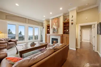 The living room is very spacious and has French doors that open onto the large deck looking out to the views of the bay and San Juan Islands. There is a lovely gas fireplace insert that has a travertine surround with built-in cabinetry matching that throughout the home.