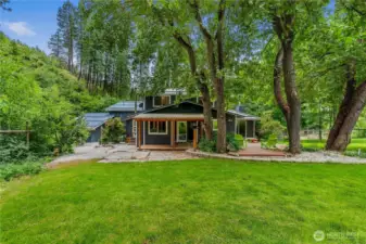 Shaded by mature trees, this backyard retreat invites slow mornings on the porch, afternoons lounging under the canopy, and evenings gathered around the fire.