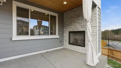 Enjoy fresh air and comfort on this covered patio with a stylish stone fireplace.