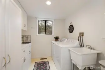The oversized laundry room serves as a guest bathroom and provides plenty of cabinetry for storage and counterspace to fold the clothes. Washer/dryer convey with home.