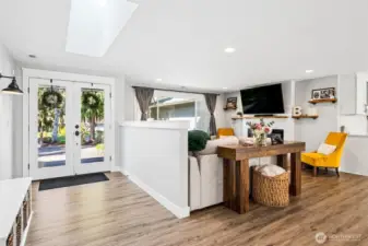 The half wall creates a gentle separation from the entry without closing anything off, so the living room still feels connected while giving you a natural place to anchor furniture and keep a little privacy from the front door. A large picture window brings in great light and a view of the front yard, while recessed lighting keeps the space bright and flexible into the evening. The fireplace wall sets up as the clear focal point, with a TV mount already in place above the mantle, making it easy to settle in and enjoy the space from day one.