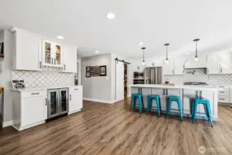 This is one of those bonus spaces that ends up getting used constantly. Tucked right between the kitchen and dining area, this beverage station is perfectly positioned for entertaining, easy access for guests without crowding the main cooking zone. The stainless beverage fridge keeps drinks ready to go, while the built-in wine glass storage underneath the upper cabinets adds both function and a little display moment. The upper cabinets feature glass fronts, which is a great spot to show off barware or keep things visually light. Finished with the same quartz counters and full-height tile backsplash, it feels fully integrated into the kitchen. It could just as easily double as a baking station or prep zone, which makes it even more useful day to day.