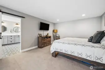 Rest and recharge in this primary suite that keeps things calm, spacious, and easy to live in. The soft dove gray walls and warm latte-toned carpeting create a relaxed, cohesive feel that carries through the home, while the generous size gives you room to truly spread out. There’s already a TV mount in place, so getting set up is simple, and the barn door leading into the ensuite adds a nice touch of character while keeping things functional. Being on the main level is a huge advantage, no stairs to think about, just easy, everyday access that works now and continues to work over time.