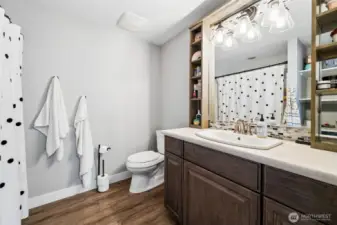 This ensuite bathroom adds another layer of convenience to the second primary suite. A full jetted tub and shower combination keeps it versatile, while the built-in shelving around the mirror offers practical storage that helps keep things organized and uncluttered. It’s a clean, straightforward space that does exactly what you want it to do. The walk-in closet nearby rounds it out nicely, giving this suite a true sense of independence and making it a great option for guests or extended living arrangements.