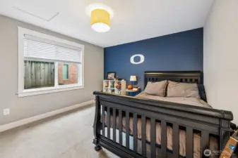 Bedroom #4 features a deep navy accent wall with the Olympia High “O” that gives it a standout feature, while the remaining walls stay in those warm latte tones that keep the room feeling grounded and consistent with the rest of the home. The plush carpet underfoot adds comfort, and the large window with privacy shades keeps the room bright but controlled. Two closets offer more storage than you typically see, which is always appreciated, and attic access adds even more functionality. It’s a versatile room that works as a bedroom, hobby space, or anything in between with just the right amount of personality.