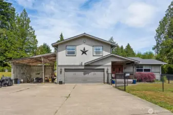Front exterior shot captures the expansive driveway & versatile covered parking area.