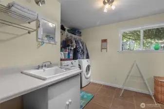Spacious laundry room and storage area on lower level, ceramic tile flooring.