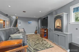 Rec room on lower floor with gas fireplace, built in media storage, and ceramic tile flooring.