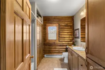 Main Bathroom – Log Accent Wall  Charming full bath with warm log accents and natural light, blending rustic character with everyday comfort.