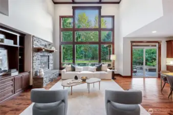 Great room with 2-story high coffered ceiling, floor-to-ceiling windows, stone surround fireplace, and built-in cabinetry.
