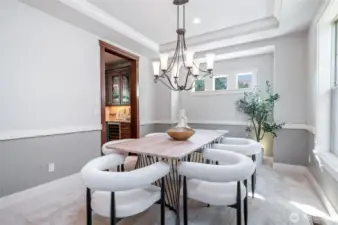 Formal dining room with recessed ceiling and adjacent Butler's bar and walk-in pantry.