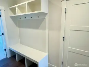 Custom built-in bench with cubbies and coat rack at entry from Garage.