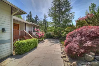 Home has a tall two car garage and is beautifully landscaped with blooming flowers, hedges, and trees.