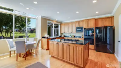 Sky-wall of windows highlight the kitchen and eating nook with serene views of the golf course