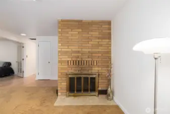 There is a medium-tone wood-burning fireplace with tile hearth. Firewood is stacked out back.