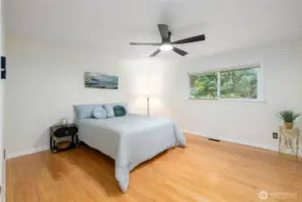 The primary bedroom has gleaming solid oak floors and a view out into the private back yard. New lighting and ceiling fan in here too.