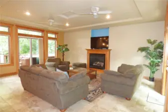 Large living room with slider leading to backyard deck. Note the tray ceiling, fans and gas fireplace.