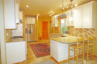 Beautiful kitchen with gas stove, walk-in pantry, granite counters, stainless appliances, tiled backsplash and eating bar.