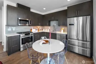 The gourmet kitchen features a gas range, stainless appliances, and opens to a deck overlooking Alki.