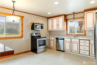 Bright kitchen with ample cabinetry, stainless steel appliances, and window with a view overlooking the mountain view.