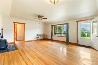 Spacious living room with hardwood floors, ceiling fan, and large picture window bringing in plenty of natural light.