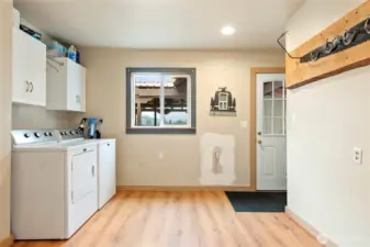 Generous laundry/mudroom with washer and dryer, built-in cabinetry, and plenty of room for storage or workspace. Convenient exterior door access adds functionality.